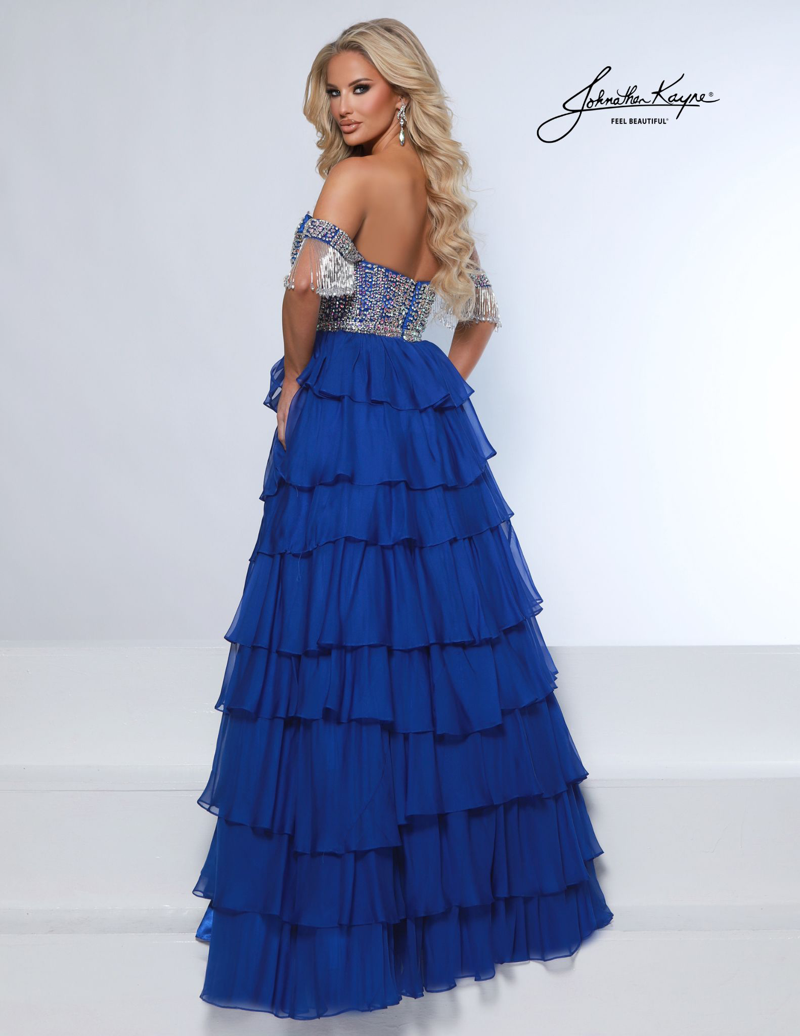 Back view of royal blue ruffle-tiered formal gown with fringe sleeve details and fitted beaded bodice - ideal for competitions. homecoming court, prom, or pageant stage.